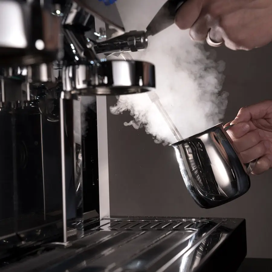 Radnik u kafiću zagreva mleko na aparatu za espresso kafu