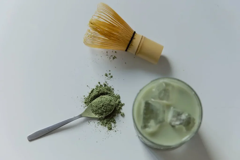 Matcha prah na stolu pored čaše Matcha latte
